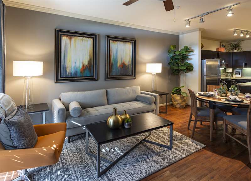 A furnished living room with a grey sofa, coffee table and the dining area behind it