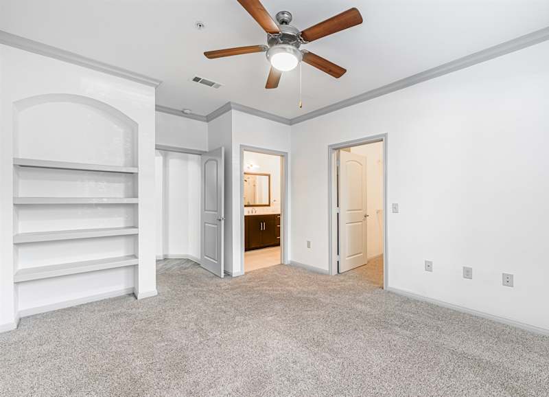 A carpeted bedroom with a ceiling fan