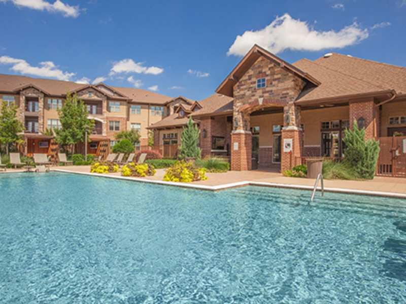 Swimming pool with lounge chairs facing the clubhouse and apartment buildings at Cypress at Lewisville