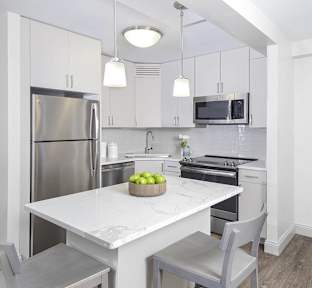 A modern kitchen with a white marble table and grey chairs.