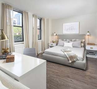 A modern bedroom with a large bed and a white desk.