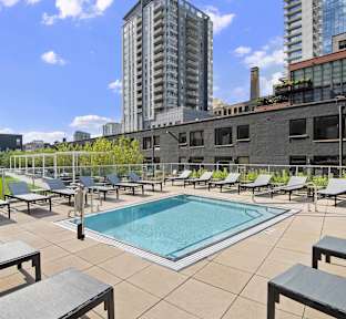 A pool surrounded by lounge chairs on a patio.