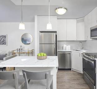 A modern kitchen with a marble table and stainless steel appliances.