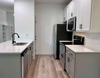 A kitchen with a black fridge and white countertops. at Madison Sierra Sun, Washington, 98374
