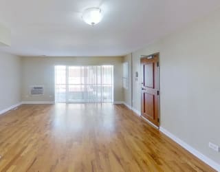 an empty living room with a large window and hardwood floors