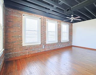 A room with a brick wall and wooden floors.
