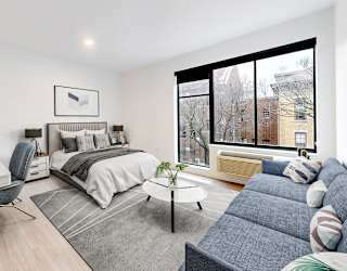 A well-lit bedroom with a bed, desk, and chair.