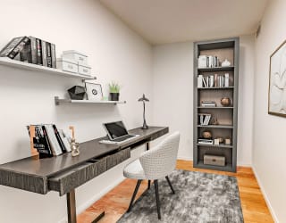 a home office with a desk with a laptop and a book shelf