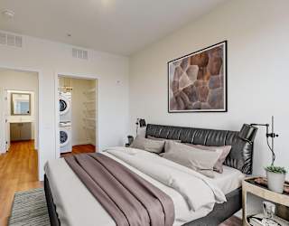A bedroom with a bed, nightstand, and a painting on the wall.