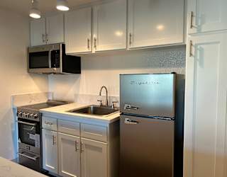 A kitchen with a stainless steel refrigerator and white cabinets.