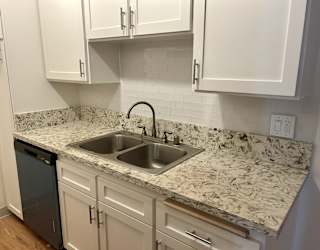 A kitchen with a marble countertop and white cabinets.