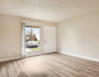 A room with a white door and a window with a view of a street.
