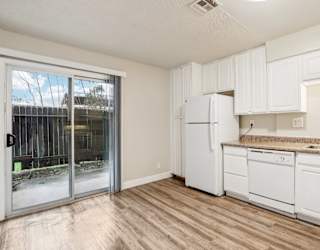 A kitchen with white cabinets and a white fridge.