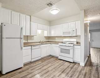 A kitchen with white appliances and cabinets.