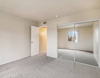 A room with a carpeted floor and a sliding glass door leading to a balcony.