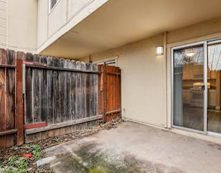 A patio with a sliding glass door and a wooden fence.