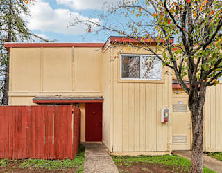 A tan building with a red door and a red fence.