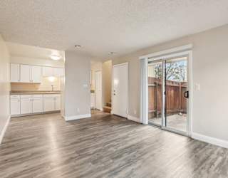 A spacious room with wooden flooring and a sliding glass door leading to a balcony.