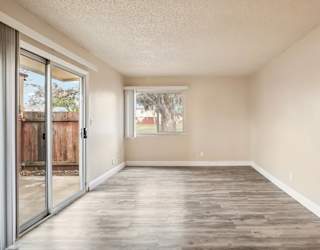 A room with a sliding glass door and wooden flooring.