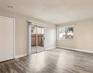 A room with a white door and a sliding glass door leading to a balcony.