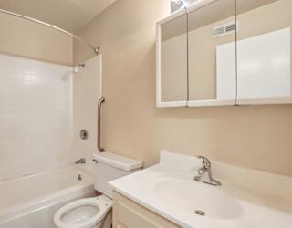 A white sink is on a counter next to a white toilet in a bathroom.
