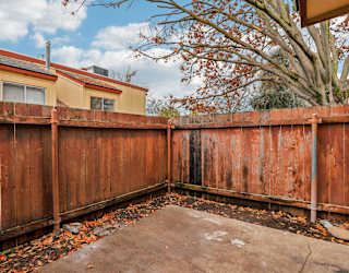 A brown wooden fence with leaves on the ground.