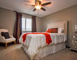 A bedroom with a bed, chair, and window.