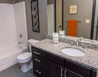 A bathroom with a toilet, sink, and a mirror.