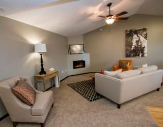 A living room with a beige couch, a chair, a lamp, a fireplace, and a fireplace