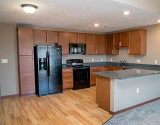 A kitchen with wooden floors and a black refrigerator.