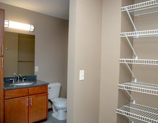 A bathroom with a toilet, sink, and shelving.