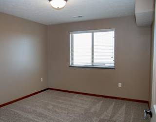 A room with a carpeted floor and a window with blinds.