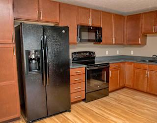 U shaped kitchen with black appliances and warm brown cabinets
