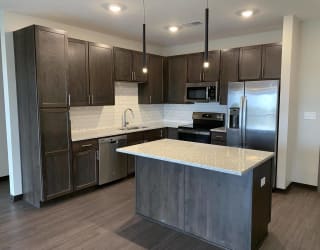 Large kitchen with dark brown cabinets, including island with room for seating