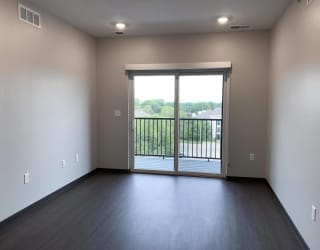 Wood floored living room with glass sliding door that opens onto balcony