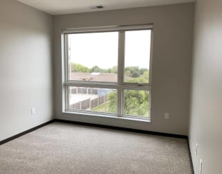 Carpeted bedroom with large floor to ceiling window looking out to north Lincoln