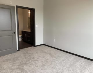 Carpeted bedroom with door to the walk in closet and door to the bathroom