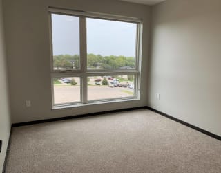 Carpeted bedroom with large floor to ceiling window looking out to north Lincoln