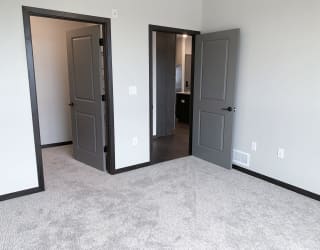 Carpeted bedroom with door to the walk in closet and door to the bathroom