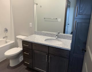 Bathroom with dark brown vanity and linen cabinet for storage and large mirror