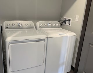 Full sized washer and dryer with rod and shelf above for storage at Haven at Uptown