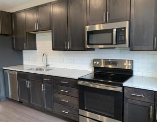 Kitchen with dark brown cabinets and matching stainless steel appliances in Peace floorplan at Haven at Uptown