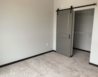 Bedroom with walk in closet enclosed by a sliding barn door