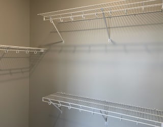 Walk in closet with multiple wire wall mount shelves for clothing and shoe storage