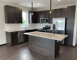 Large kitchen with warm dark brown cabinets, stainless steel appliances, and an island with extra storage