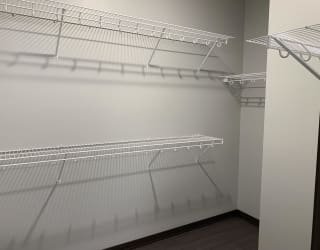 Walk in closet with multiple wire wall mount shelves for clothing and shoe storage