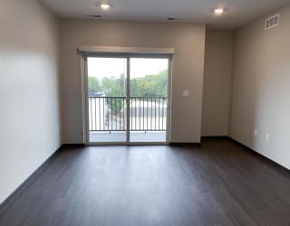 Empty living area with wood floors and sliding door leading to patio