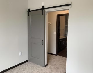 Open barn door looking into a pass through walk in closet in a one bedroom apartment in Lincoln