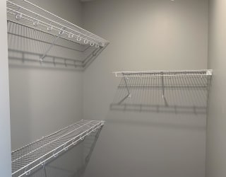 Large empty walk in closet with upper and lower wire racks for clothing storage