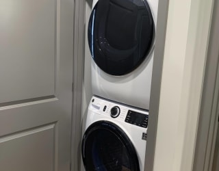 Stacked front loader washer and dryer in a closet with door.